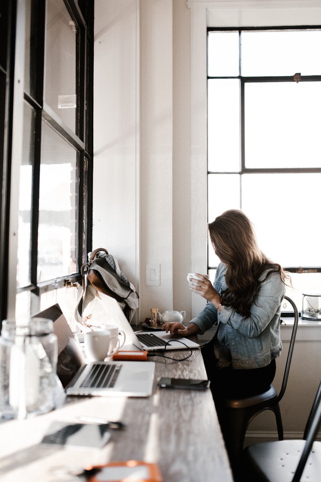 woman drinking out of her mug and working on her computer