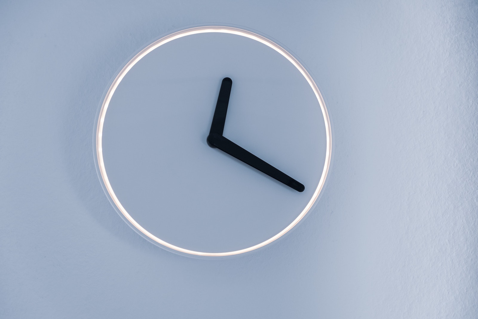 minimalist analog clock on blue-grey wall