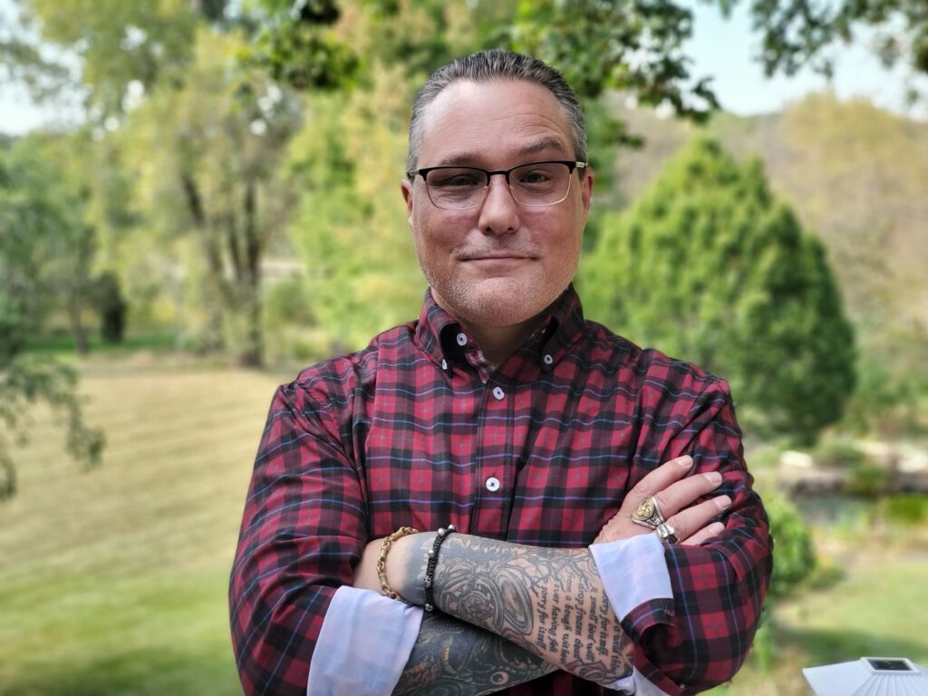 man with arm tattoos standing with his arms crossed