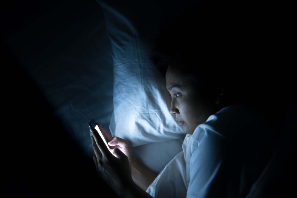 girl scrolling on her phone at night