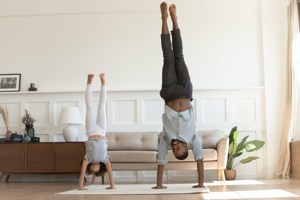 young girl and father doing handstands in living room